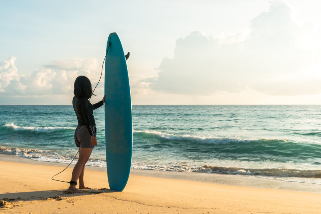 a woman holding a surfboard on a beach.
